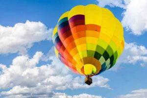 Low angle closeup shot of a colorful hot air balloon against a blue cloudy sky